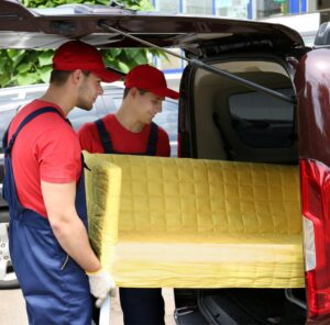 Günstig umziehen in Rotenburg: Umzugshelfer laden ein gelbes Sofa in einen Transporter