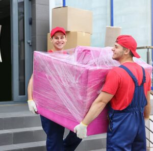 Zwei Umzugshelfer tragen ein in Folie gepacktes Möbelstück – Umzug in Rotenburg