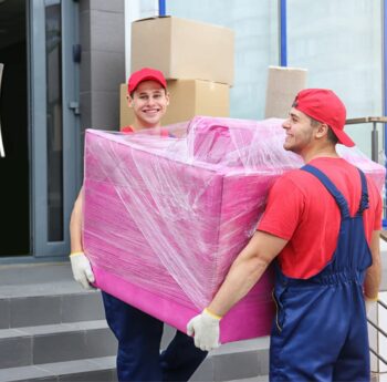 Zwei Umzugshelfer tragen ein in Folie gepacktes Möbelstück – Umzug in Rotenburg
